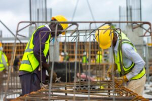 Construction workers with hard hats and safety vests working on site.